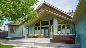 A house with a covered patio, a hot tub, and a lawn.