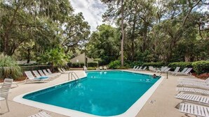 A rectangular swimming pool with a white deck, surrounded by lounge chairs and trees. - Harbour Town Gem: Serene Lagoon Views & Steps to the Lighthouse (Hilton Head Island)