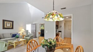 A living room with a dining table, chairs, a sofa, a lamp, and a hanging light fixture. - Harbour Town Gem: Serene Lagoon Views & Steps to the Lighthouse (Hilton Head Island)