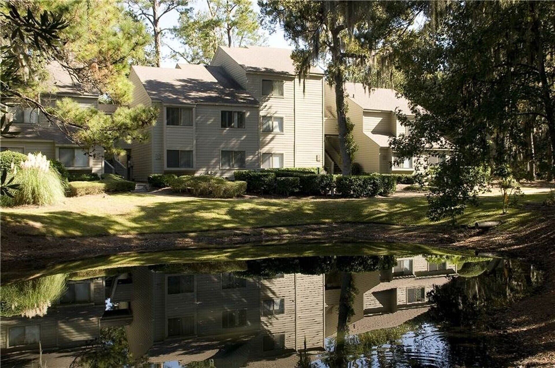 A two-story residential building with a reflective pond in front.