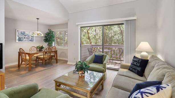 A living room with a dining area, a sofa, a coffee table, and a TV. - Harbour Town Gem: Serene Lagoon Views & Steps to the Lighthouse (Hilton Head Island)