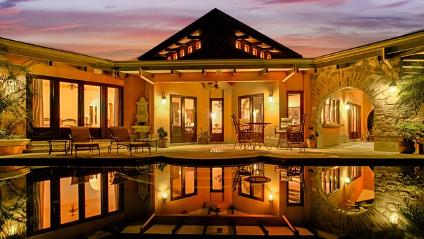 Ein luxuriöses Haus mit Pool, Sitzgelegenheiten im Freien und einem Steingewölbe.
