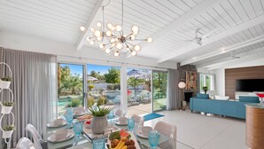 A modern dining area with a glass table, white chairs, and a ceiling light fixture.