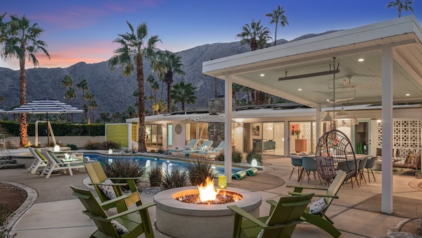 A modern outdoor patio with a fire pit, lounge chairs, and a pool area.