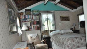 A cozy bedroom with a bed, a chair, a desk, and a bookshelf. - A cozy country "Doll House," with everything to meet your needs. (Hector)