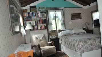 Une chambre confortable avec un lit, une chaise, un bureau et une bibliothèque.