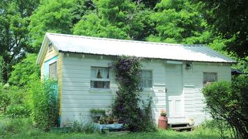 Une petite maison à un étage, dotée d’un toit à pignon et entourée d’une végétation luxuriante.