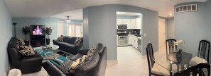 Relax in a spacious living area with a sofa set, flat-screen TV, and glass coffee table.