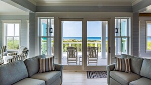 A spacious living room with a view of the beach through large sliding glass doors.