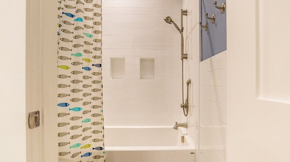A bathroom with a bathtub, a shower, and a towel rack.
