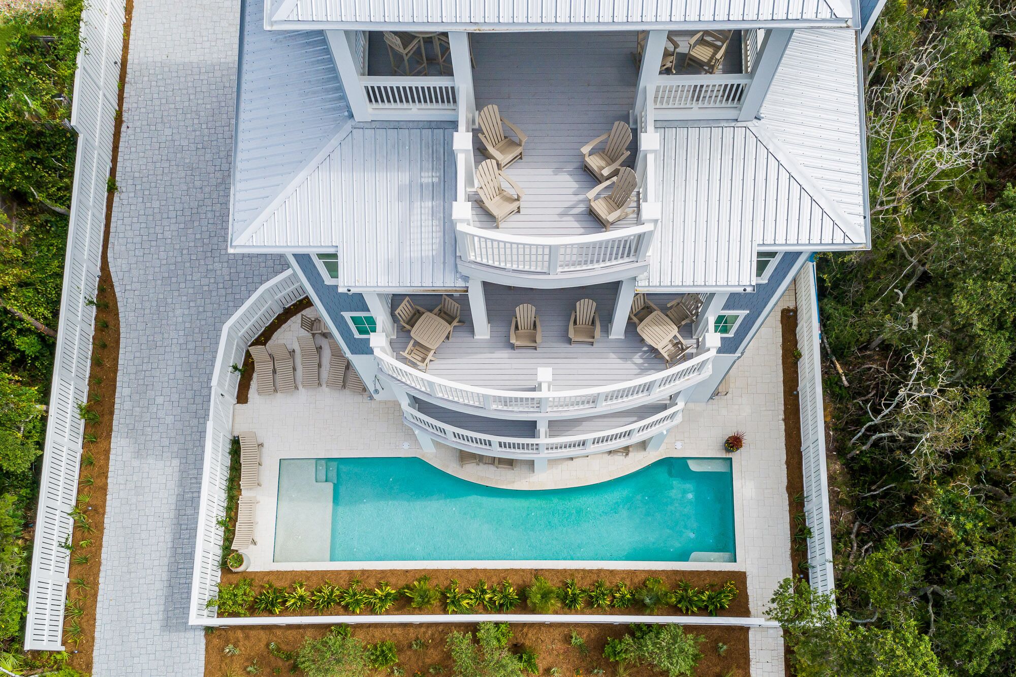 A multi-level house with a pool, outdoor seating, and a landscaped garden.