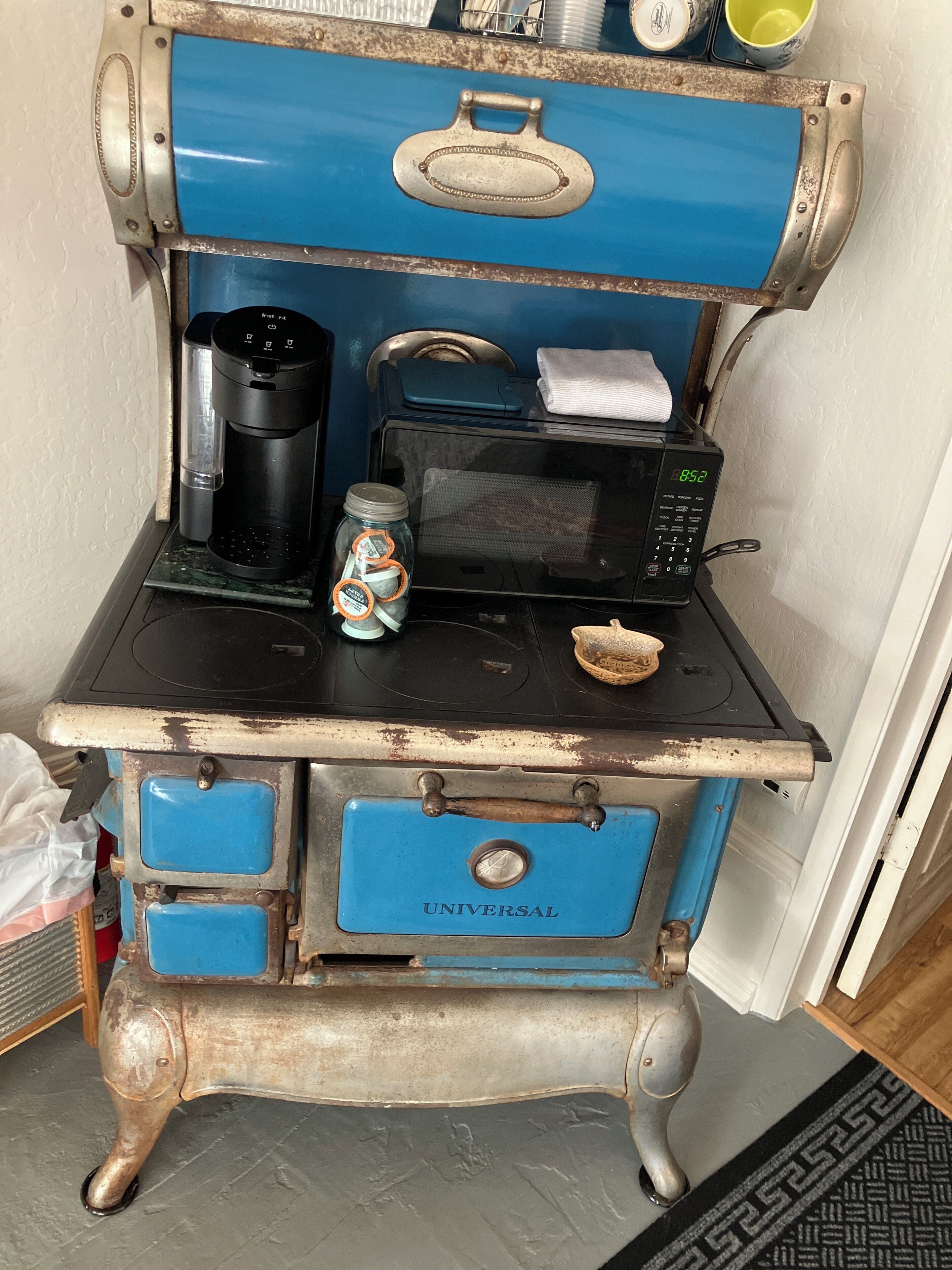 A kitchenette with a coffee maker, microwave, and a jar of sugar.