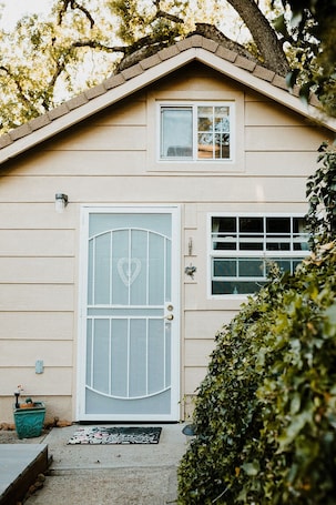 A single-story house with a beige exterior, a white front door with a heart-shaped window, and a small window above the door.
