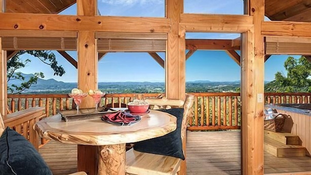 Een houten terras met een tafel en stoelen, met uitzicht op een prachtig landschap.