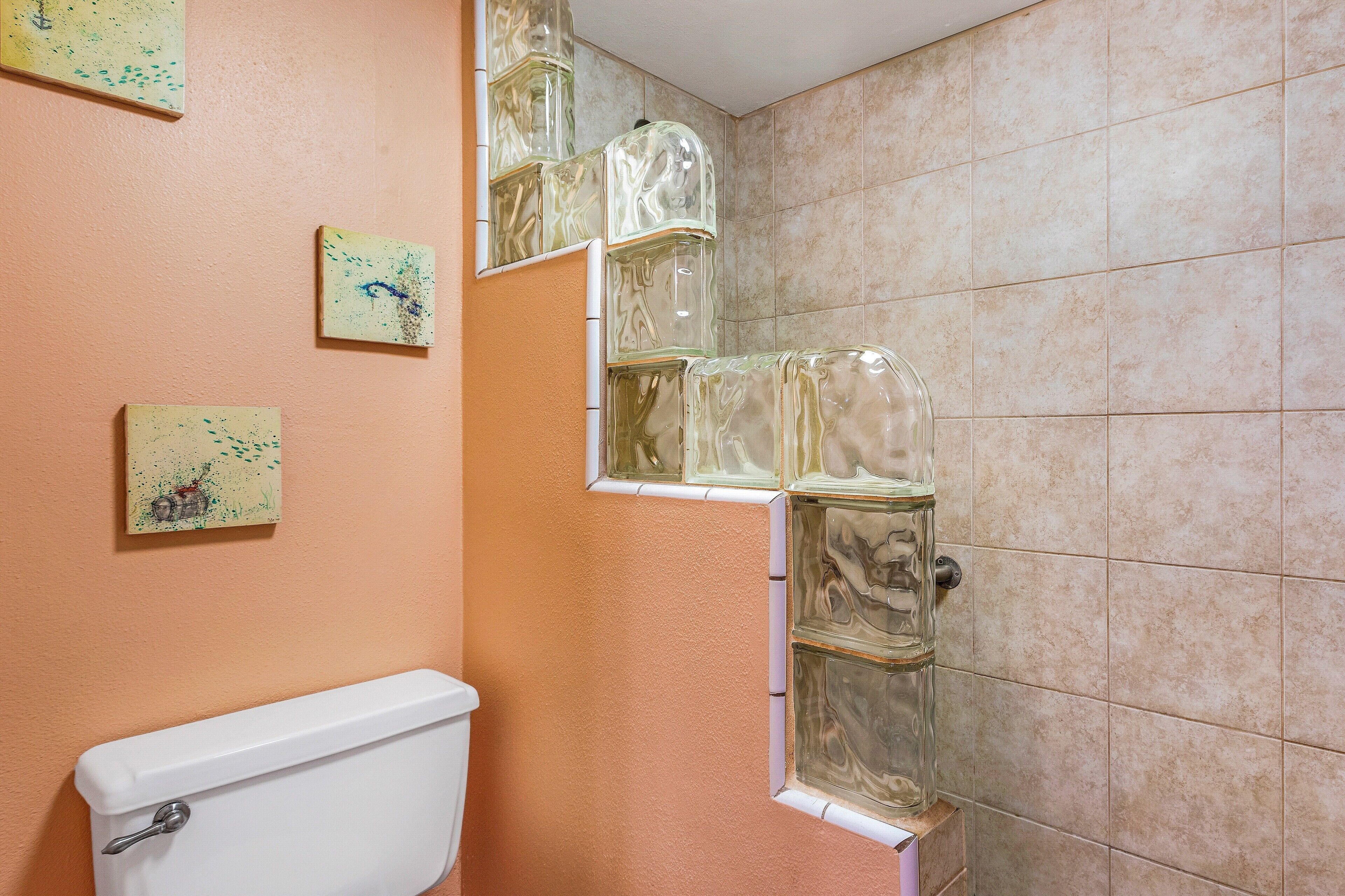 A bathroom with a toilet, a glass shower enclosure, and a tiled wall.