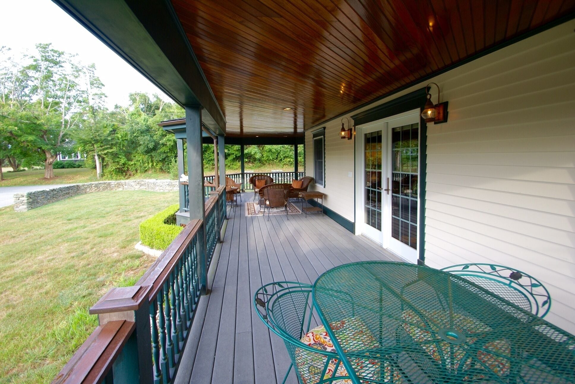 The porch features comfortable wicker seating for 7 and a 4 place dining table