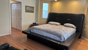Une chambre à coucher avec un grand lit, une table de chevet, une chaise et une porte.