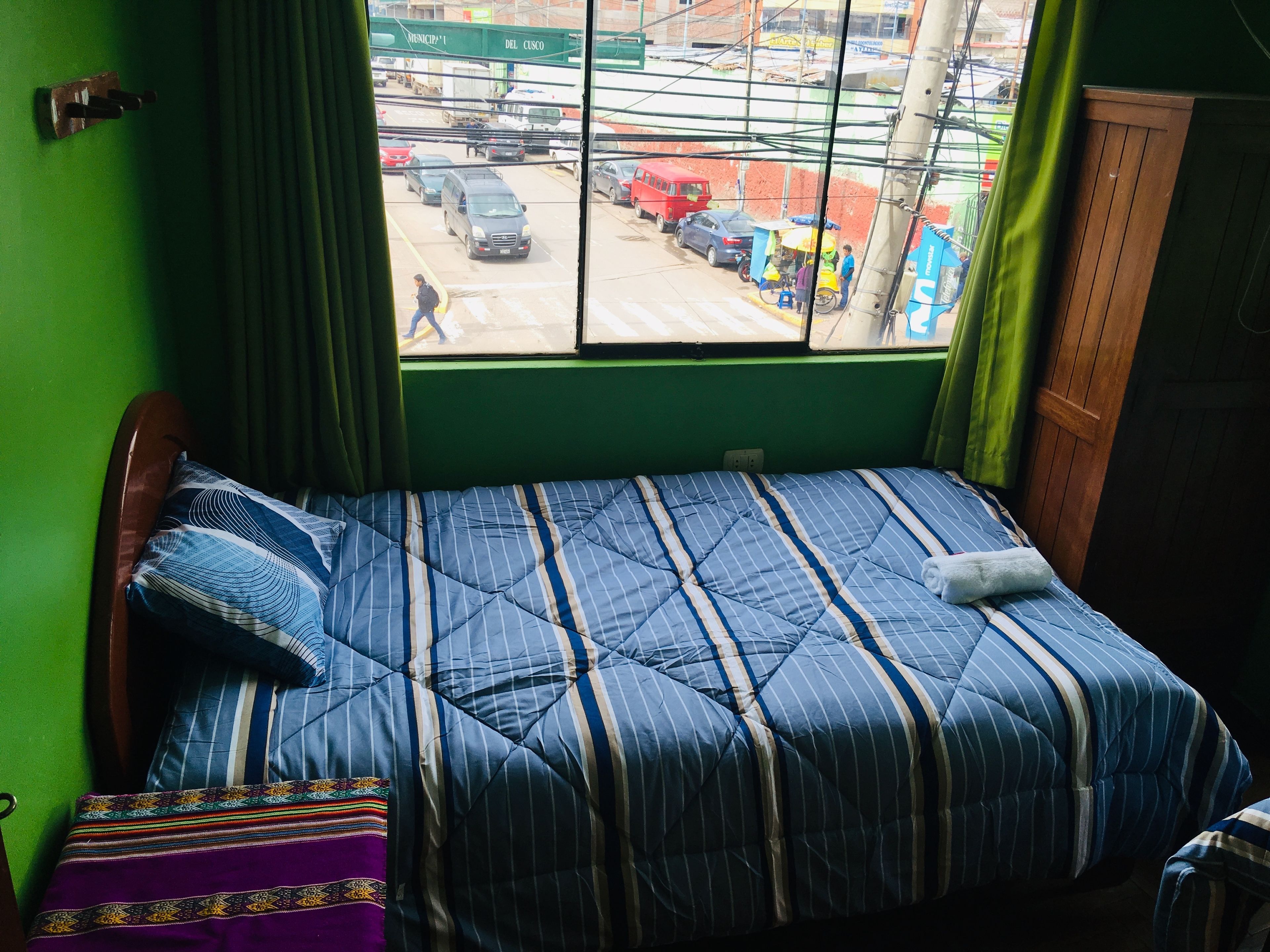 Una habitación con una cama, una ventana y vista a la calle.