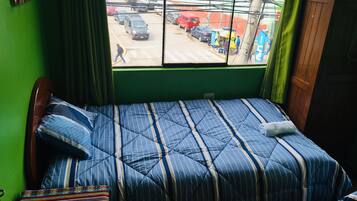 Una habitación con una cama, una ventana y vista a la calle.