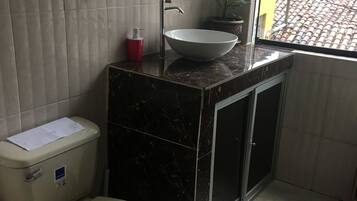 Un baño pequeño con inodoro, lavabo y ventana con vistas a una obra en construcción.