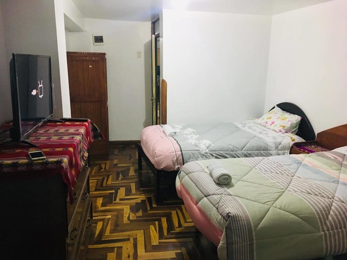 Una habitación pequeña y funcional con dos camas, un armario y una televisión.