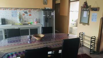 Una cocina equipada con refrigerador, microondas y una mesa de comedor con sillas.