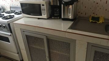Uma cozinha com micro-ondas, cafeteira e chaleira no balcão.
