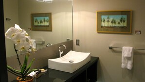 A bathroom with a white sink, a mirror, a towel rack, and two framed paintings on the wall. - Suites at 118 (Bloomington)