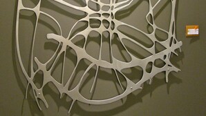 A wall-mounted abstract metal sculpture with a complex, web-like structure. - Suites at 118 (Bloomington)
