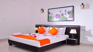 A neatly made bed with orange and white bedding, two bedside lamps, and a framed floral artwork on the wall. - Wasu Villa Hotel Dambulla (Dambulla)