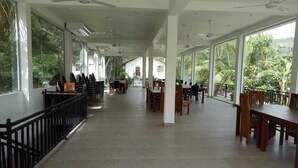 A spacious indoor area with high ceilings, large windows, and multiple tables and chairs arranged for dining. - Wasu Villa Hotel Dambulla (Dambulla)