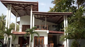 A two-story house with a covered patio, outdoor seating, and a motorcycle parked in front. - Wasu Villa Hotel Dambulla (Dambulla)