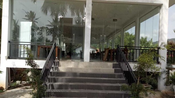 A building with a staircase leading to a covered entrance, large glass windows, and potted plants. - Wasu Villa Hotel Dambulla (Dambulla)