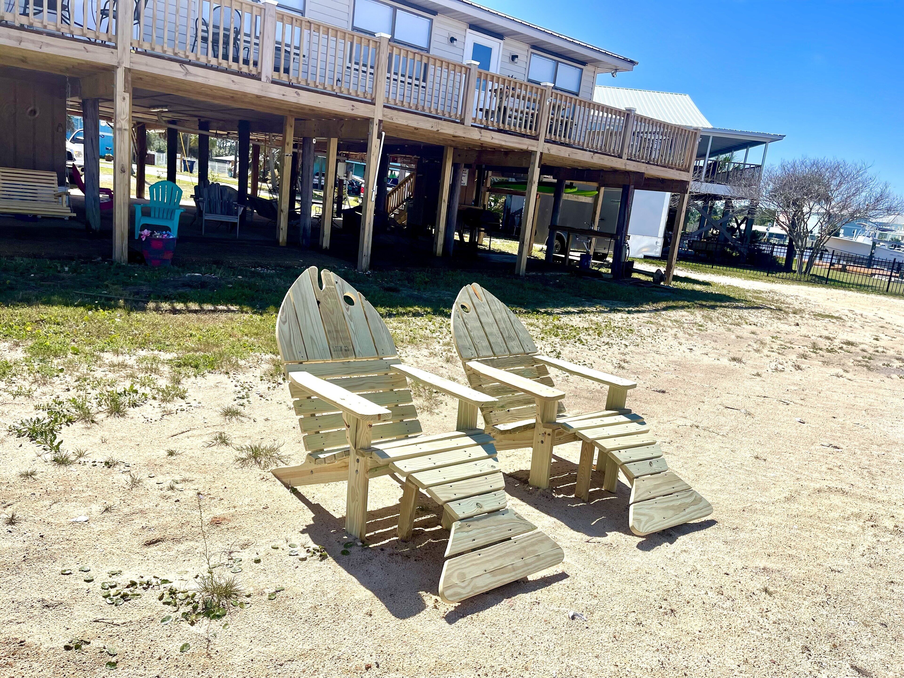 Une terrasse en bois située au bord de la plage, avec un espace salon couvert et un bâtiment en arrière-plan.
