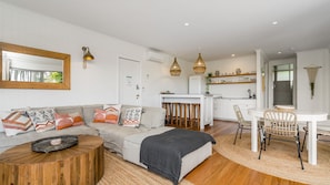 A modern living room with a sofa, coffee table, and dining area. - EAST COAST ESCAPES | Lighthouse Lounge (Byron Bay)