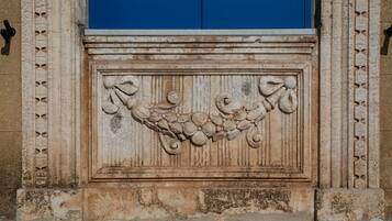 A stone relief with a grapevine design, flanked by two blue doors with shutters.