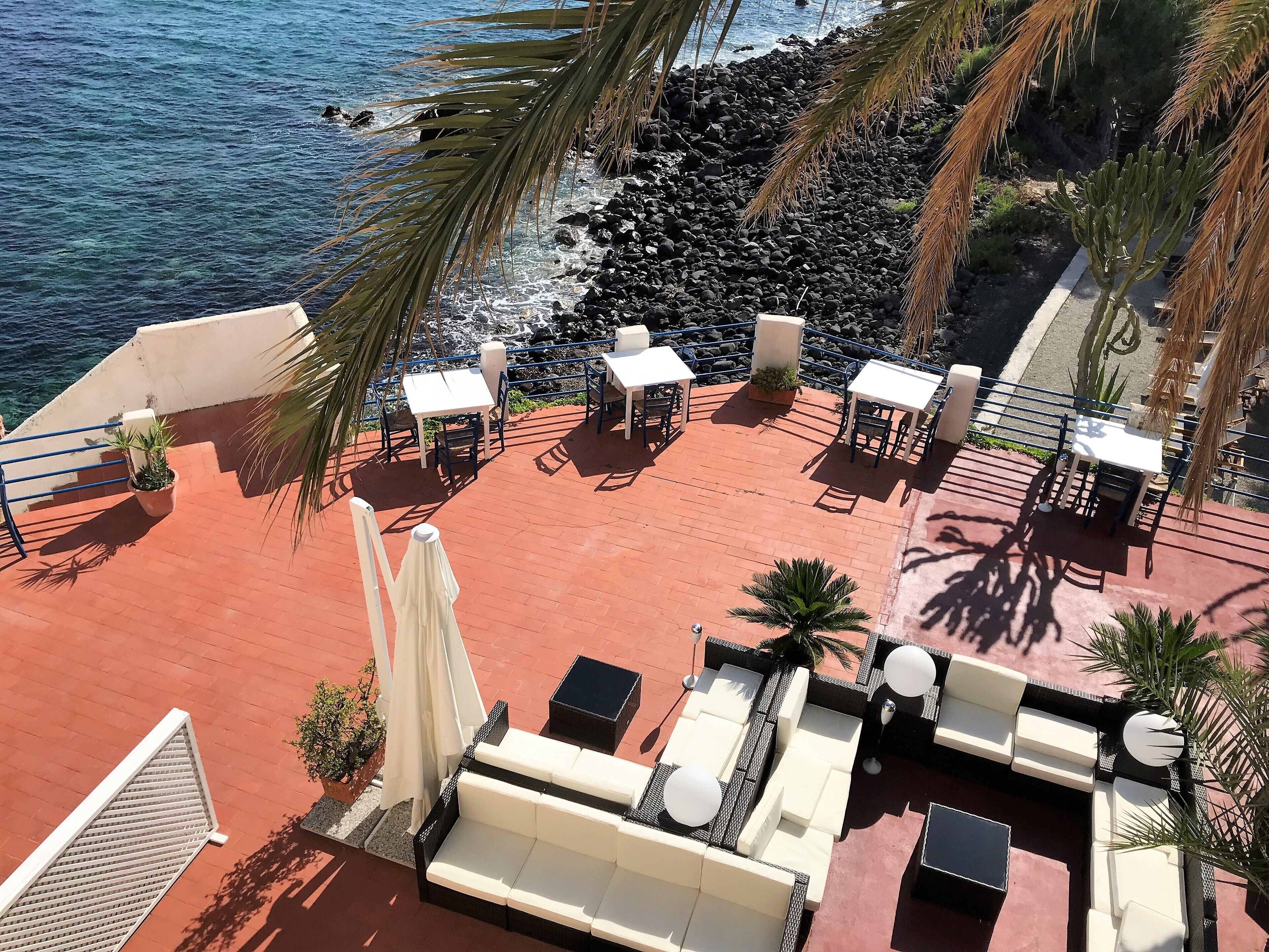 A rooftop terrace with outdoor seating, a railing, and a view of the ocean.