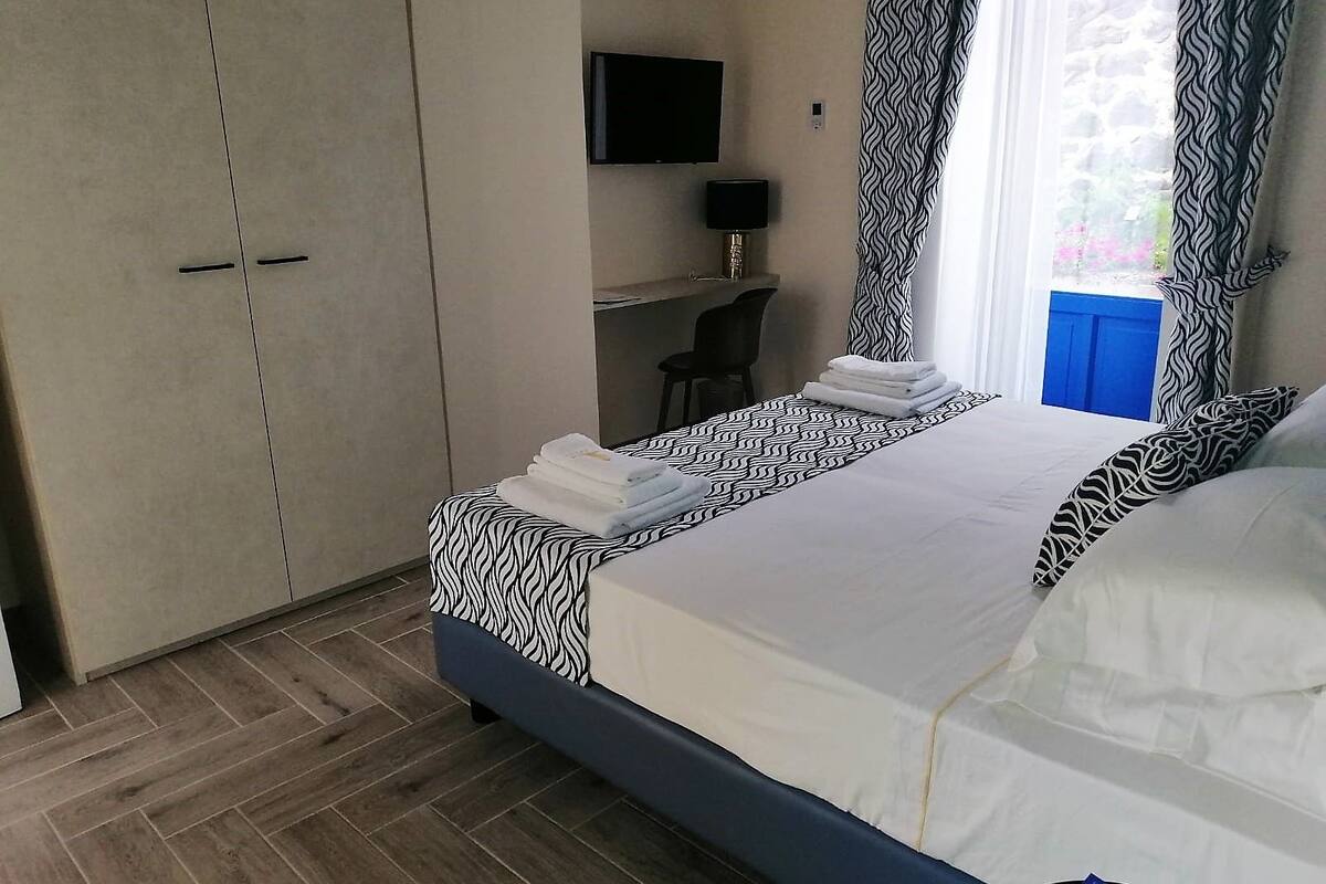 Ein Hotelzimmer mit Bett, Schreibtisch, Stuhl, Fernseher und Kleiderschrank.