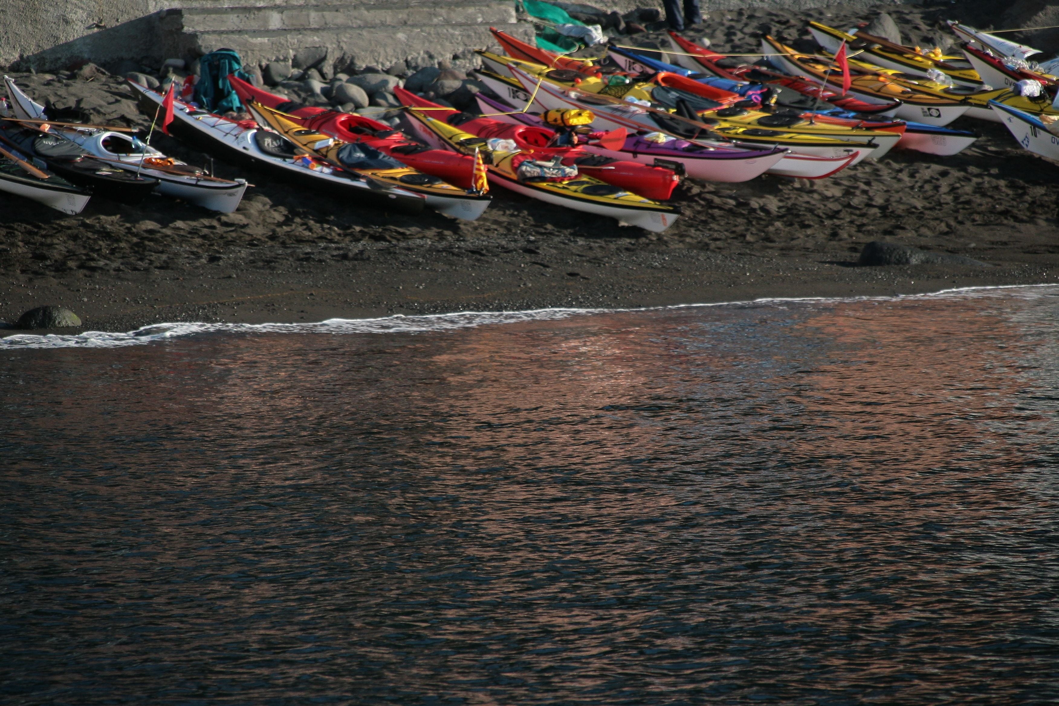 A beach with several small boats lined up on the sand.