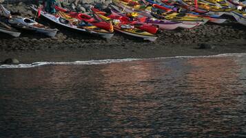 A beach with several small boats lined up on the sand.