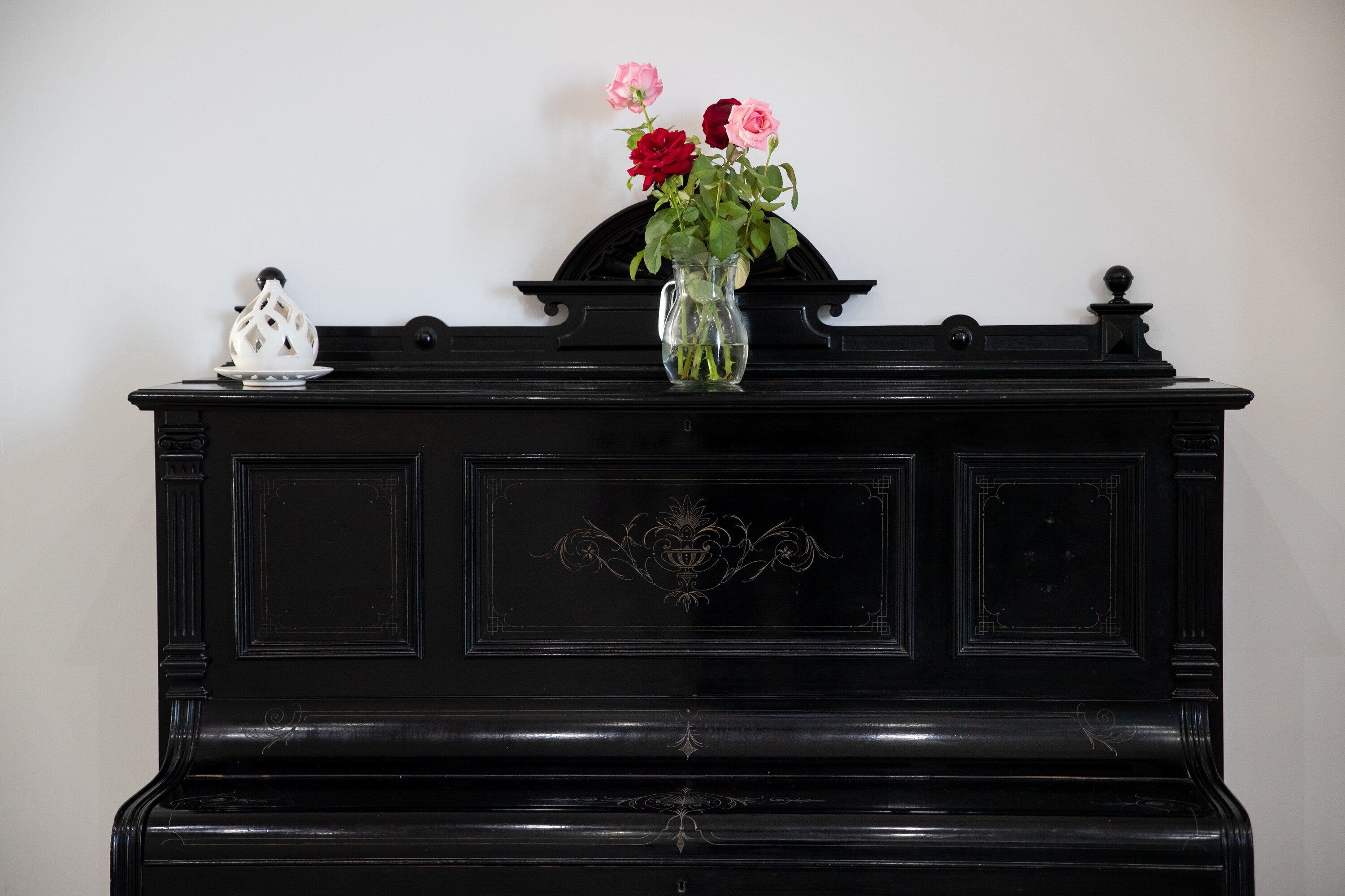 A black piano with a vase of flowers on top.