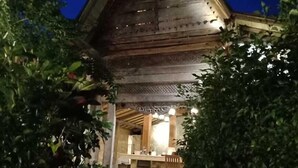 A wooden building with a sloped roof, a bar area with seating, and a stone pathway leading to the entrance. - Coconut Lodge (Mlonggo)