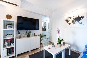 A modern living room with a flat-screen TV, white cabinetry, a coffee table, and a world map on the wall.