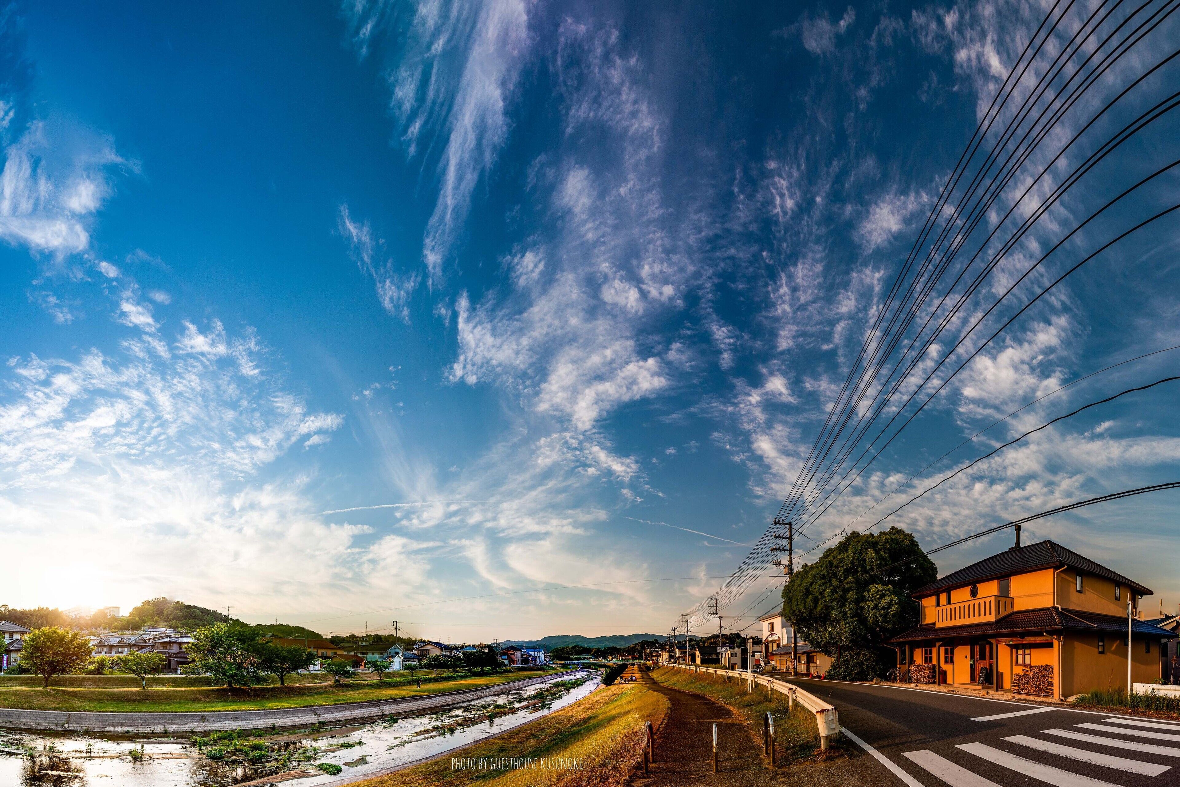 A residential street with houses, a clear sky, and power lines.