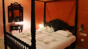 Una cama con dosel con sábanas blancas y un cojín decorativo.
