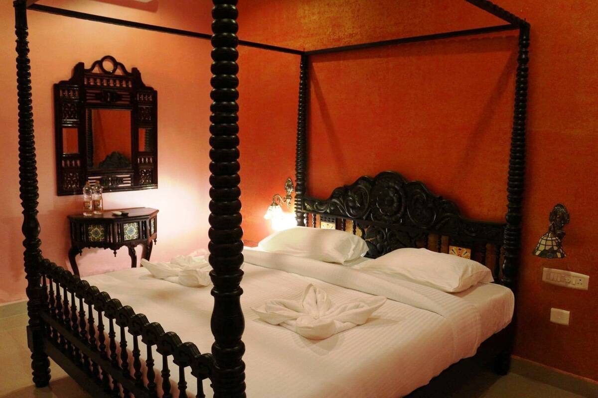 Una cama con dosel con sábanas blancas y un cojín decorativo.