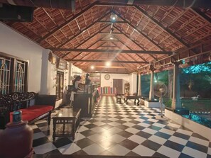 A room with a checkered floor, a wooden ceiling, and a view of a pond.