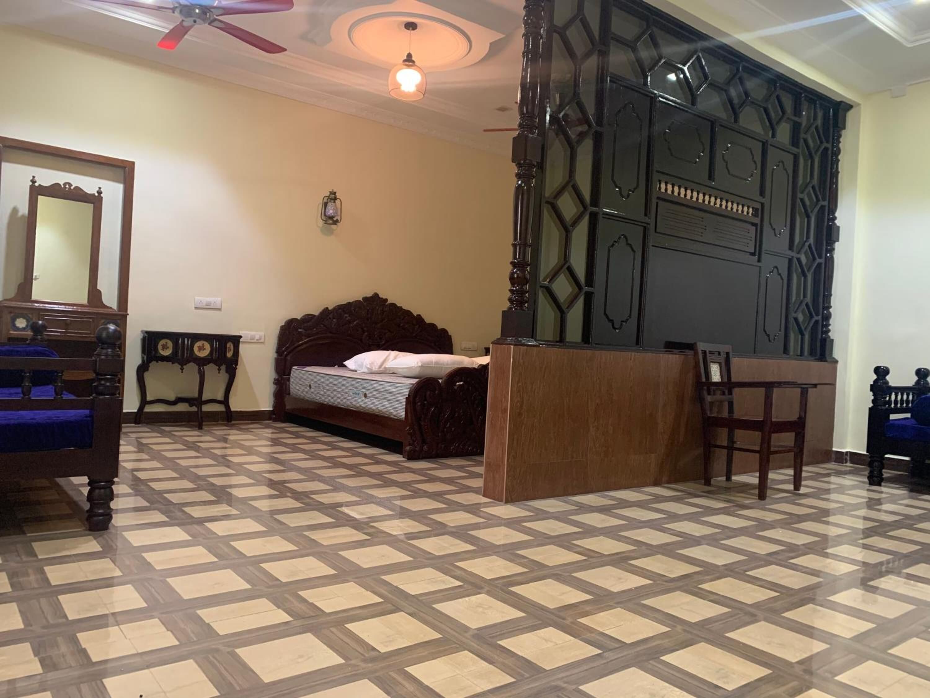 A bedroom with a checkered floor, a bed with a wooden headboard, a nightstand, a dresser, a mirror, and a ceiling fan.