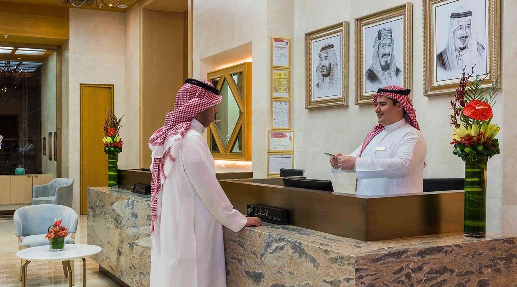 A reception area with marble counters, framed portraits on the wall, and a reception desk.