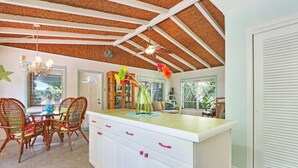 A kitchen with a central island, white cabinetry, and a thatched ceiling. - Old Florida Surf Cottage (Jensen Beach)
